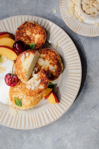 Tortitas de queso con cereza, nectarina, yogur. Mesa de desayuno