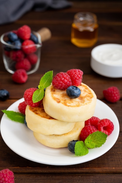 Tortitas de requesón con bayas frescas, crema agria y miel syrniki tradicional