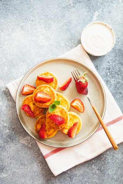 Tortitas de requesón buñuelos de ricotta o syrniki con menta y fresas Desayuno matutino saludable y delicioso