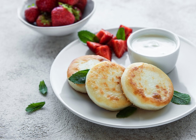 Tortitas de requesón buñuelos de ricotta en placa de cerámica con fresa fresca