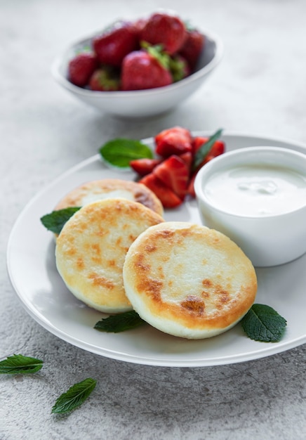 Foto tortitas de requesón buñuelos de ricotta en placa de cerámica con fresa fresca