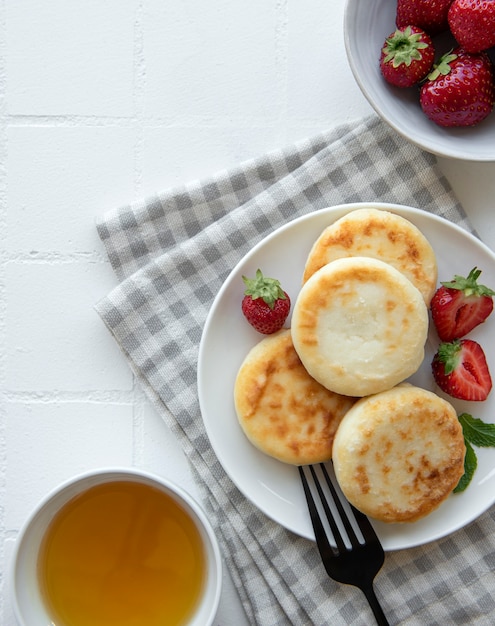 Tortitas de requesón buñuelos de ricotta en placa de cerámica con fresa fresca