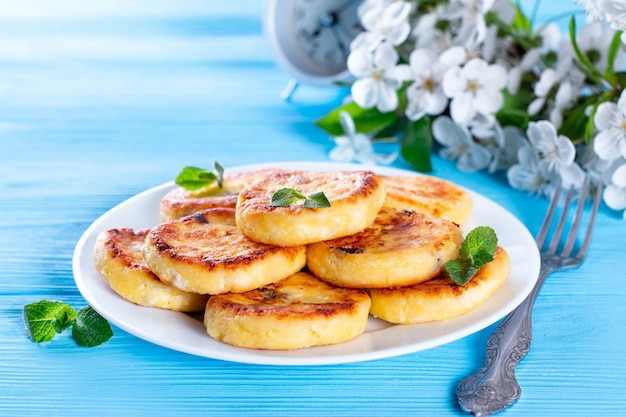 Tortitas de requesón o syrniki con menta sobre un fondo azul. Desayuno o almuerzo saludable