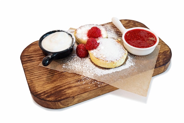 Tortitas de requesón en una tabla de servir de madera aislado sobre fondo blanco.