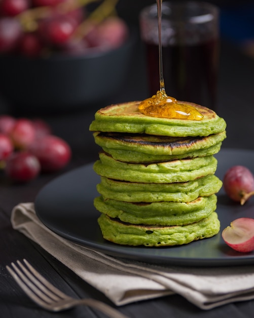 Tortitas verdes con té matcha o espinacas, aderezado con miel y uvas rojas.