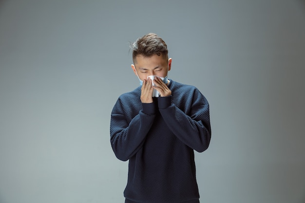 Toser, estornudar. Hombre chino en máscara protectora azul posando. Prevención de los síntomas respiratorios de la neumonía como fiebre, dolor de cabeza. Ilustración de coronavirus chino. Cuidado de la salud, concepto de medicina.