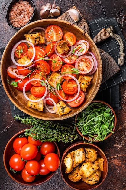 Toskanischer Panzanella-Salat, vegetarischer klassischer Salat mit Tomaten, Zwiebeln und Croutons. Dunkler Hintergrund. Ansicht von oben.