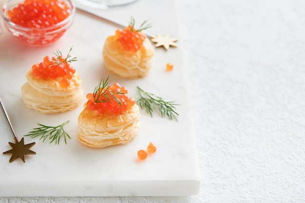 Tosta de caviar rojo de salmón Canape de Navidad o tostada con caviar roja en un plato blanco sobre un fondo claro Idea para el bocadillo de Navidad Comida gourmet Textura de caviar Mariscos