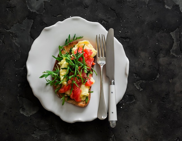 Tosta con tortilla de aguacate, salmón y rúcula en un fondo oscuro vista superior deliciosas tapas para el desayuno