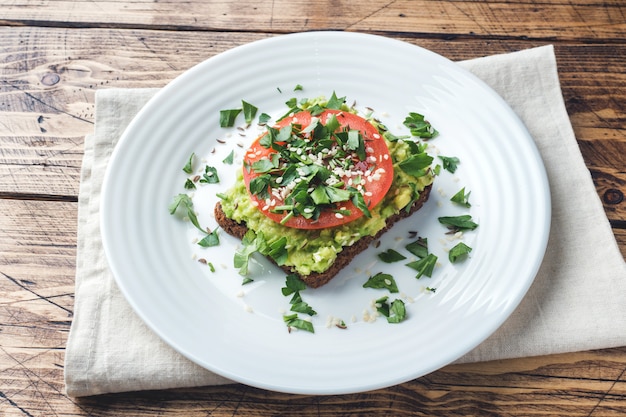 Tostada de aguacate. Tostada saludable con puré de aguacate y tomates en un plato.