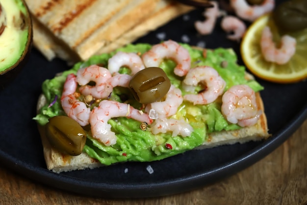 Foto tostada de guacamole con aguacate, gambas y aceitunas healthy snack keto