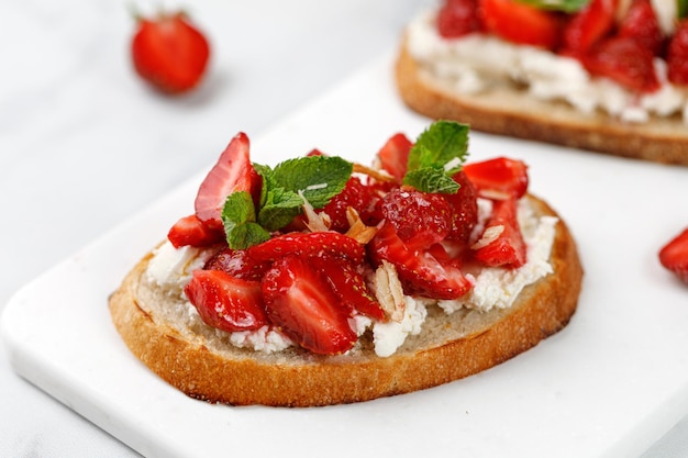 Tostada con requesón de fresas ricotta miel almendras y menta Postre dulce de fresas