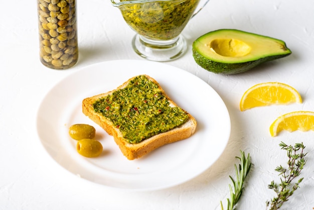 Tostadas con aceitunas de aguacate y salsa chimichurri en un plato blanco Comida vegetariana saludable Fondo blanco