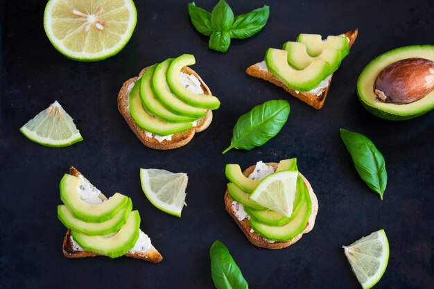 Tostadas con aguacate, crema de queso cuajada y lima en la oscuridad