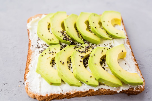 Tostadas con aguacate fresco, queso crema y semillas de chia sobre concreto gris