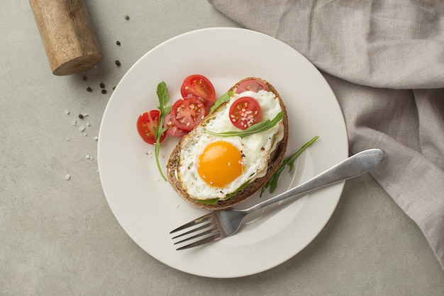 Tostadas con aguacate de huevo y otras verduras sobre un fondo gris en un plato de desayuno saludable