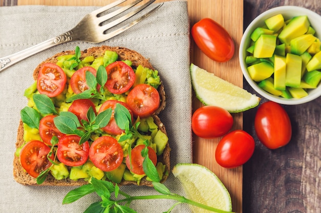 Tostadas con aguacate, tomate y albahaca sobre mesa de madera rústica