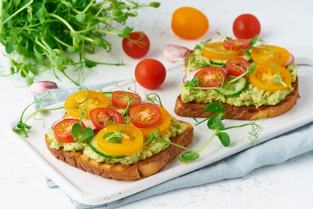 Tostadas de aguacate con tomates cherry y hierbas, desayuno, primer plano