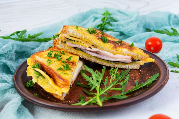 Tostadas asadas en huevos revueltos con hierbas de jamón y queso cheddar Delicioso sándwich de desayuno a la parrilla