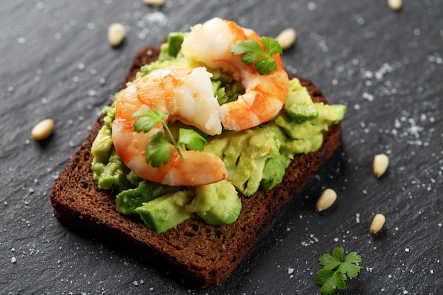 Tostadas con camarones, aguacate, nueces, perejil en mesa oscura