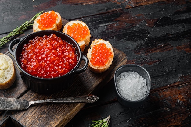 Tostadas de canapés con caviar rojo sobre un fondo antiguo de mesa de madera oscura con espacio para copiar texto