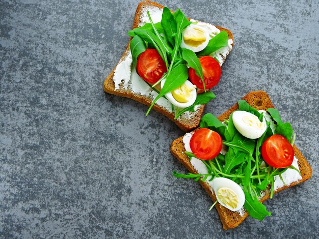 Tostadas de centeno y trigo con rúcula, huevos de codorniz y tomates cherry.