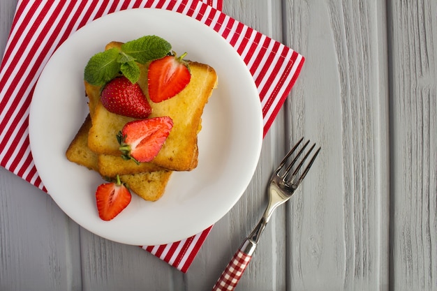 Tostadas francesas con fresas en la placa blanca.