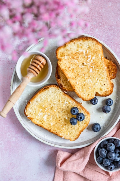 Tostadas francesas rociadas con miel y copos de coco y arándanos Concepto de desayuno