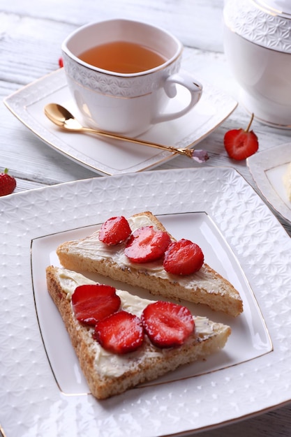 Tostadas frescas con mantequilla casera y fresas frescas en un plato sobre fondo de madera