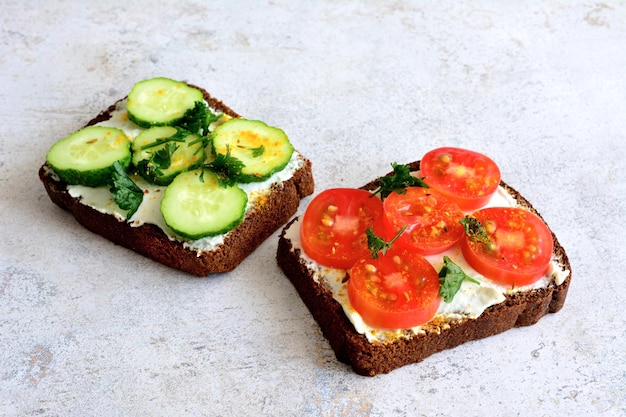 tostadas integrales con queso blando, pepino y rodajas de tomate aisladas en un fondo pastel