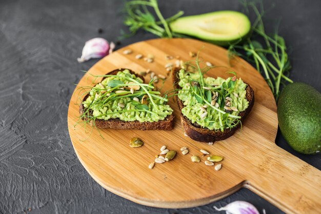 Tostadas integrales recién cocidas con untable de aguacate y brotes microverdes