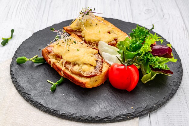 Tostadas de jamón, queso y ensalada en un plato. En la mesa de madera