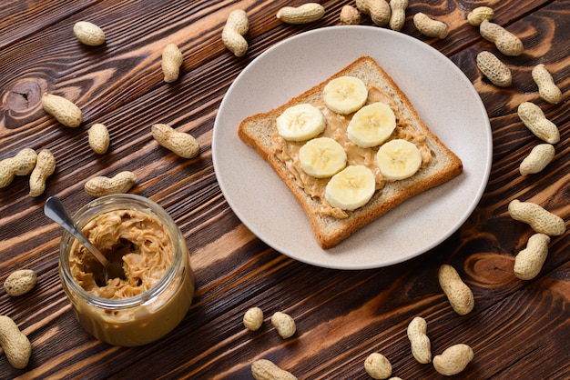 Tostadas de mantequilla de maní con rodajas de plátano en la mesa de madera