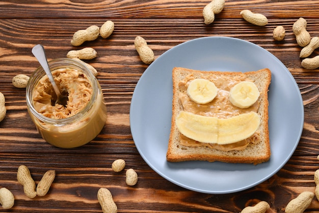 Tostadas de mantequilla de maní con rodajas de plátano sobre fondo de madera