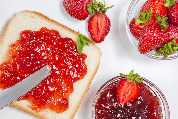 Foto tostadas con mermelada de fresa para el desayuno sobre fondo de madera rústica blanca vista superior