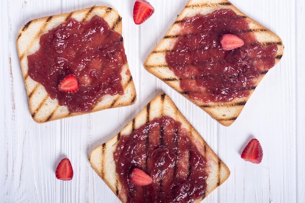 Tostadas con mermelada de fresa sobre fondo de madera rústica