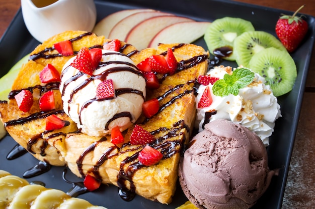 Tostadas de miel. Postre dulce servido con fruta variada y helado.