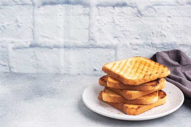 Tostadas de pan crujiente para sándwiches en un plato sobre una mesa de hormigón gris