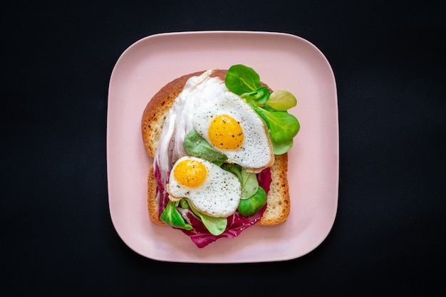 Tostadas de pan con huevos fritos y ensalada verde.