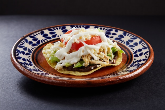 Foto tostadas de pollo con base de frijoles lechuga tomate queso y crema