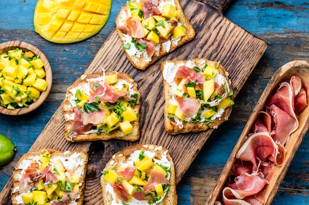 Tostadas con queso crema, jamón y mango.