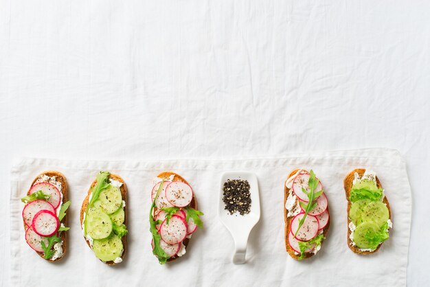 Unas tostadas de rábano y pepino con ricotta, ensalada y papel