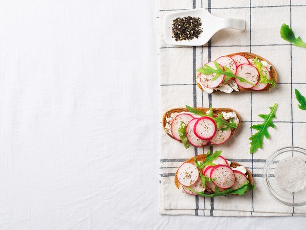 Unas tostadas de rábano con ricotta y ensalada en servilleta con sal y papel