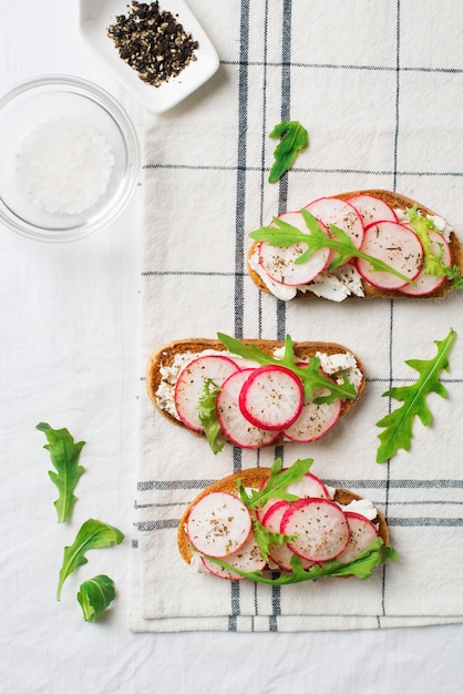 Unas tostadas de rábano con ricotta y ensalada en servilleta con sal y papel