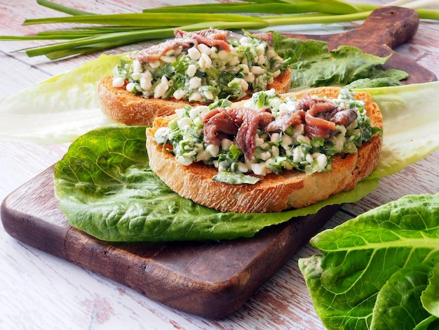 Tostadas con requesón o anchoa de ricotta y hierbas en el fondo de tomates lechuga con ajo