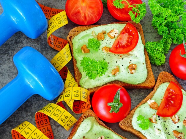 Tostadas con requesón verde y nueces y tomate. Cinta métrica. Mancuernas Comida de fitness.