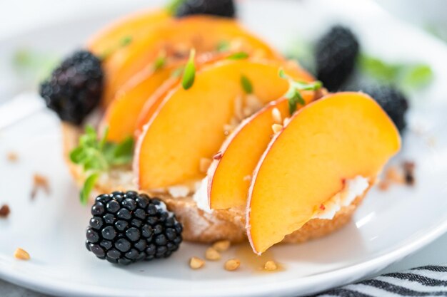 Tostadas de ricotta de melocotón adornadas con moras en un plato blanco.