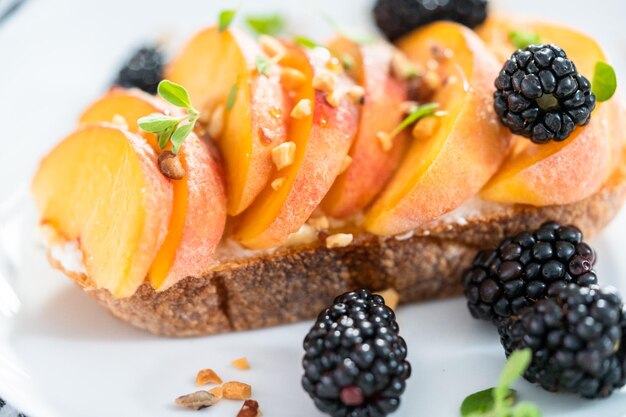 Tostadas de ricotta de melocotón adornadas con moras en un plato blanco.