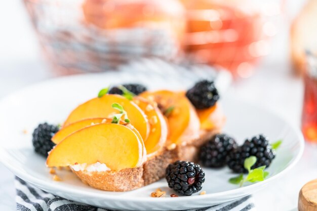 Tostadas de ricotta de melocotón adornadas con moras en un plato blanco.