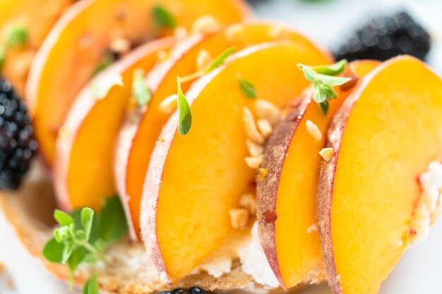 Tostadas de ricotta de melocotón adornadas con moras en un plato blanco.